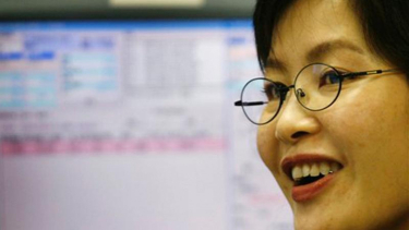 Seorang pialang di Hong Kong tersenyum dengan naiknya harga saham