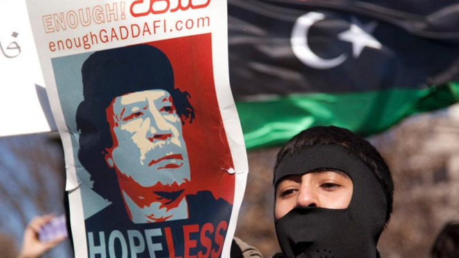 Demonstran membawa poster anti pemimpin Libya Moammar Khadafi