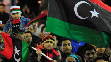 Rakyat Libya mengibarkan bendera nasional. 