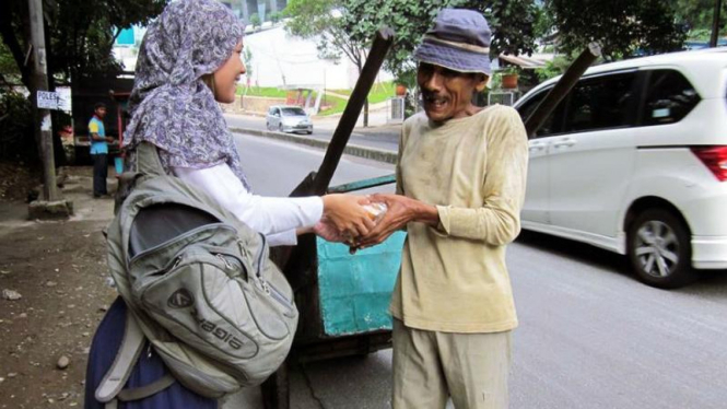 Seorang wanita sedang memberi sedekah kepada pemulung di Jakarta. 