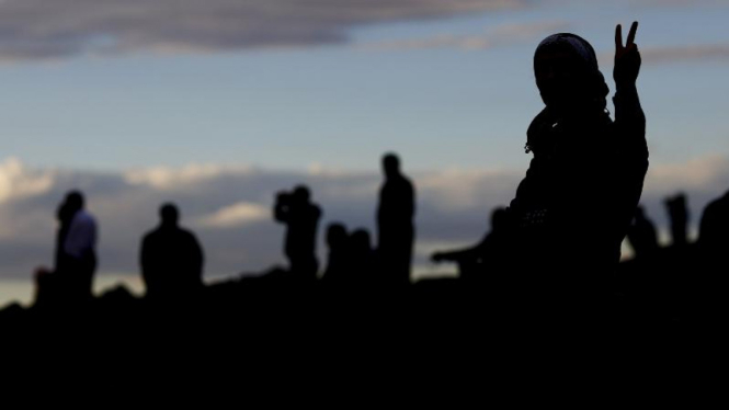 Pejuang Kurdi di Kobani memberi isyarat tangan tanda kemenangan, 19 Oktober.