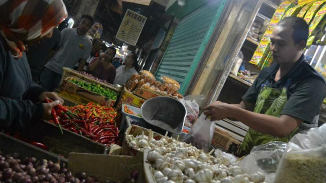 Seorang pembeli sedang memilih cabe keriting di pasar.