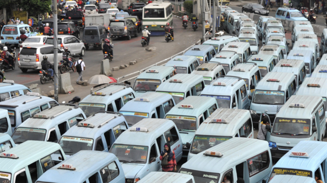 Penumpang berjalan di antara deretan mikrolet di Terminal Kampung Melayu, Jakarta Timur