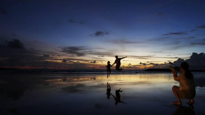 Turis asing menikmati Keindahan Pantai Kuta, Bali.