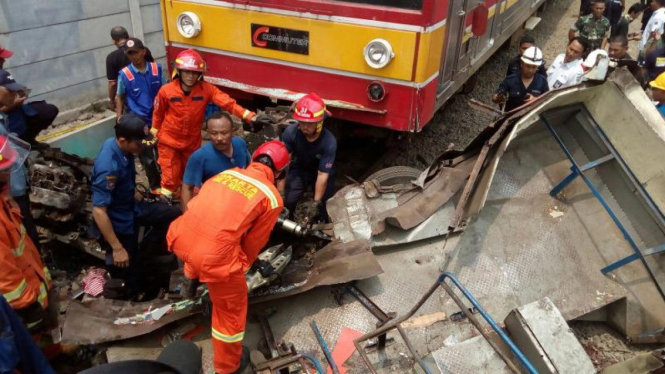 Petugas evakuasi bangkai Metro Mini yang ditabrak KRL di Angke, Jakut.