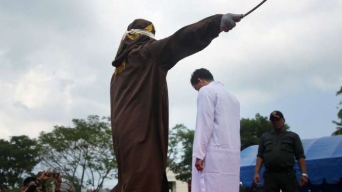 Terpidana pelanggar peraturan daerah (qanun) Syariat Islam (tengah) menjalani hukuman cambuk di halaman Masjid Rukoh, Kecamatan Syiah Kuala, Banda Aceh, Aceh, Selasa (1/3/2016)