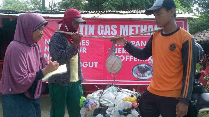 Suyatmi, menimbang sampah plastik yang ditukarkan pemulung untuk berbelanja di kantinnya. Kantin makanan milik Suyatmi memang hanya menggunakan sampah sebagai alat transaksi pembayaran, Senin (14/3/2016)