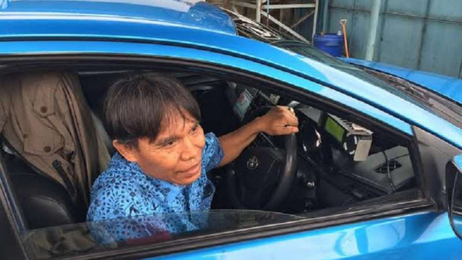 Karmono saat mengemudikan taksinya.