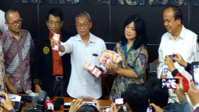 Busyro Muqoddas menunjukkan uang yang diberikan polisi kepada keluarga Siyono.