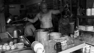 Asiang, sedang meracik kopi untuk pelanggannya. Pria berkepala plontos ini selalu 'telanjang' selama melayani pelanggannya dari pukul 04.00-14.00.