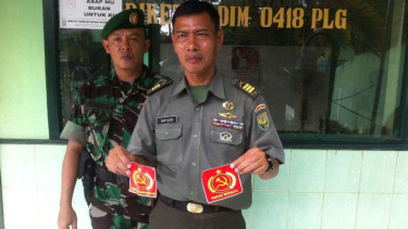 Pasi Inteldim Palembang, Kapten Inf. Suryatin, menunjukan stiker palu arit