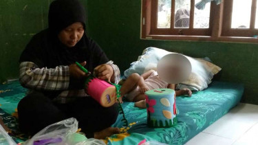 Maemunah saat membuat celengan hias di depan bayi Haura