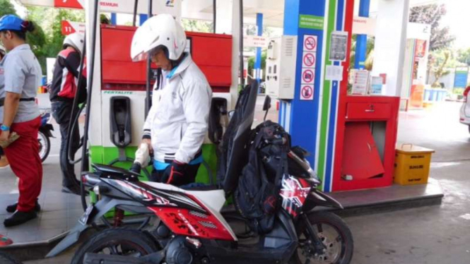 Pengendara motor mengisi bahan bakar di SPBU.