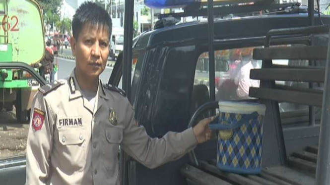 Petugas kepolisian dengan termos tempat menaruh mayat bayi