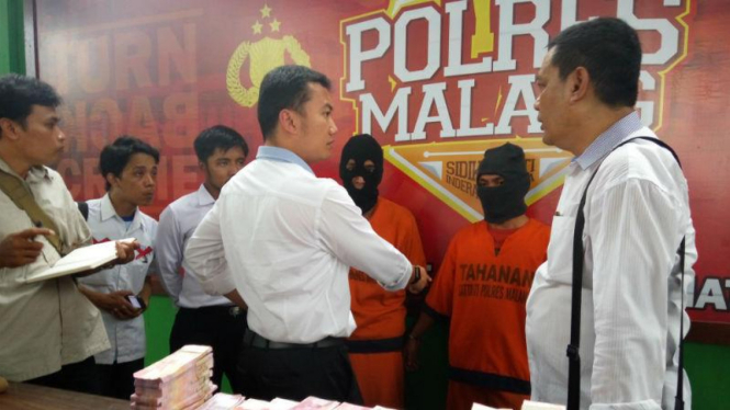 Kedua tersangka dengan barang bukti uang palsu saat gelar perkara di Polres Malang