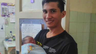 Theodorus Mamile, mengendong anaknya yang lahir pada 17 Agustus 2016 di Manado.