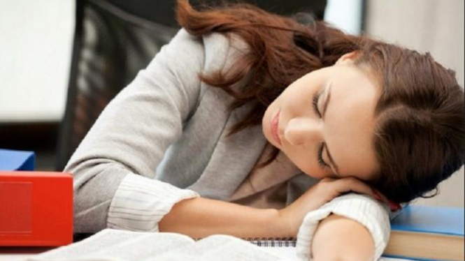 Wanita tertidur di meja kerja.