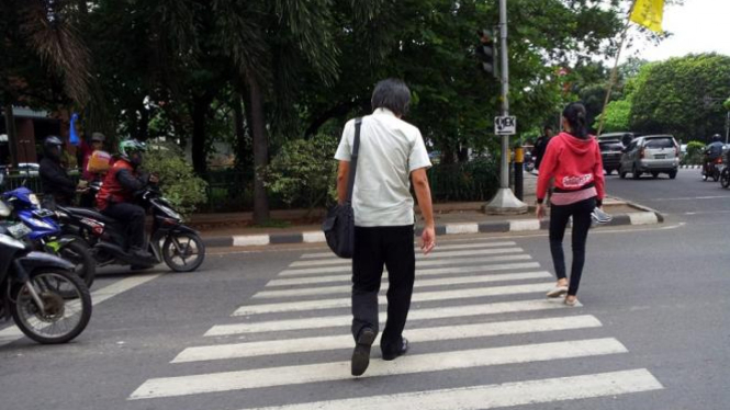 Pedestrian menyeberang di zebra cross.