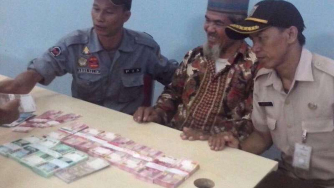 Pengemis Muklis M (tengah) dengan uang Rp90 juta.