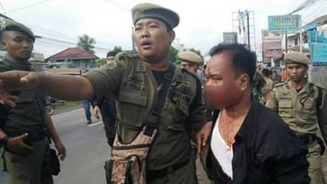 Wakil Ketua DPRD Kabupaten Mesuji Musholi Rais saat diselamatkan anggota Satpol PP usai dipukuli warga di rumah duka Wakil Bupati Mesuji, Minggu (16/10/2016)
