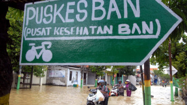 Pengendara melintasi banjir yang menggenangi Jalan utama di Kabupaten Sampang