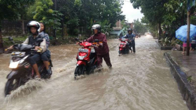 Sejumlah pengendara sepeda motor mendorong kendaraannya yang mogok akibat banjir di jalur alternatif Gedebage Kota, Bandung, Jawa Barat,  pada Jumat, 28 Oktober 2016.