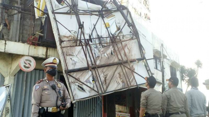Sebuah papan reklame roboh dan menimpa bangunan ruko di pertigaan lampu merah Jalan Arif Rahman Hakim, Depok, Jawa Barat, pada Kamis, 19 Januari 2017.