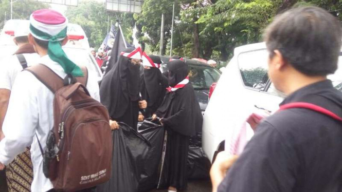 Para perempuan bercadar memungut sampah di Aksi 112.