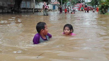 Dua anak bermain air di lokasi banjir Bukit Duri, Jakarta Selatan.