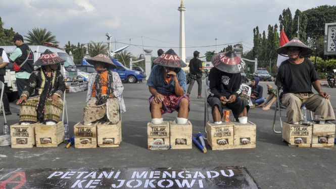 Para petani Kendeng saat beraksi memasung kaki dengan adonan semen di dekat Istana Negara sebagai bentuk protes mereka atas pendirian pabrik semen di Rembang, Jawa Tengah. 