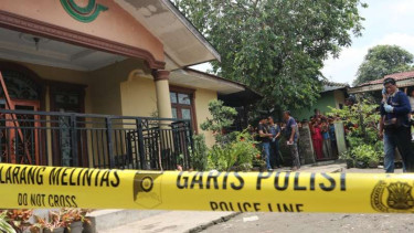 Polisi berjaga di depan rumah korban pembunuhan satu keluarga di Medan.