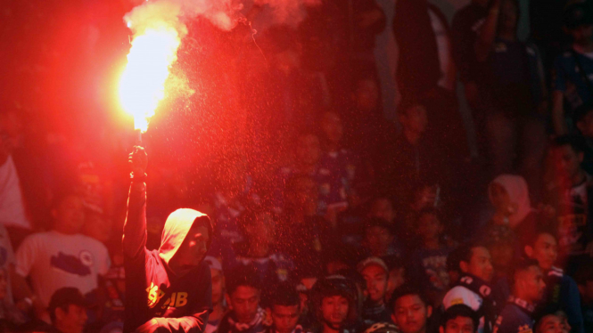 Ilustrasi suporter bakar flare saat pertandingan.