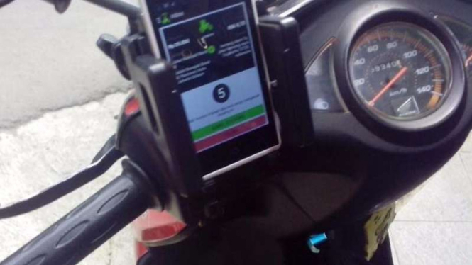 Ponsel ditaruh di dasbor motor.