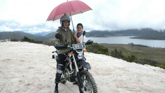 Presiden Jokowi sebelum naik motor trail dipayungi Ibu Negara saat meninjau proyek jalan Trans Papua beberapa waktu lalu.