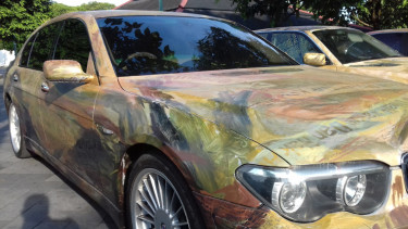 Mobil BMW yang dilukis potongan koran.