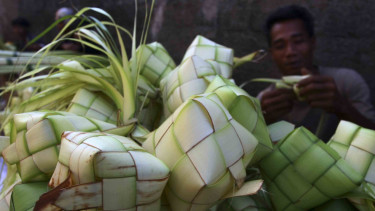 Seorang penjual menganyam ketupat dagangannya di Pasar Ciputat, Tangerang Selatan, Banten