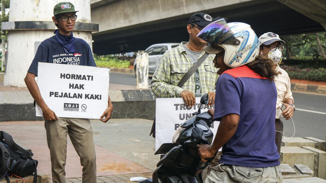 Aktivis trotoar hadang pengendara motor yang naik ke trotoar.