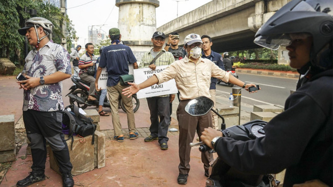 Aktivis trotoar hadang pengendara motor yang akan naiki trotoar.