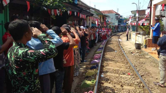 Upacara bendera persis di pinggir rel kereta api.