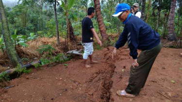 Sekretaris Kecamatan Cisompet, Nurbani Tamim menunjukkan tanah retak 