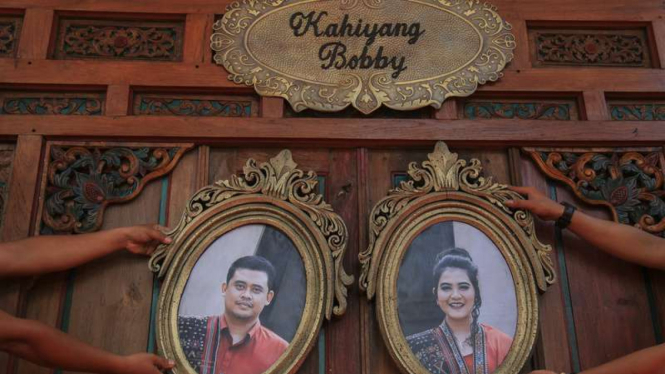 Petugas memasang foto putri Presiden Joko Widodo, Kahiyang Ayu (kanan) dengan Bobby Nasution (kiri) di Gedung Graha Saba, Solo, Jawa Tengah, Senin (6/11/2017).