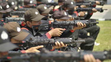 Polisi sedang memakai senjata laras panjang.