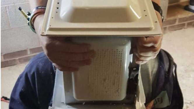 Pria menyemen kepalanya ke dalam microwave