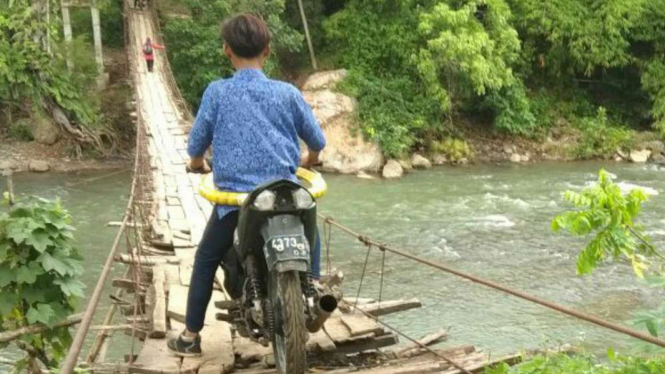Beberapa warga bergantian melewati Jembatan gantung Rawayan di Garut.