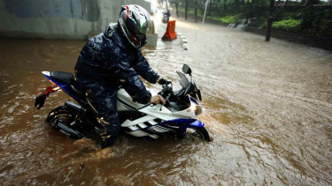 Pengendara sepeda motor melintasi banjir yang menggenangi kawasan Semanggi