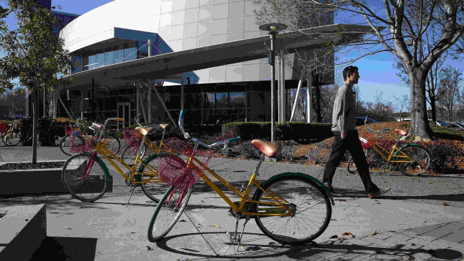 Serorang melintas di antara sepeda Google di markas pusat Google