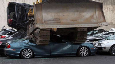 Puluhan mobil diratakan dengan buldozer.