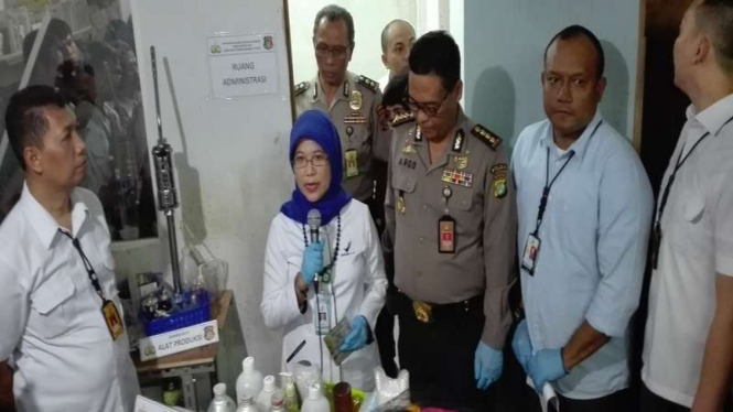 Polisi saat memeriksa pabrik parfum palsu yang digerebek.