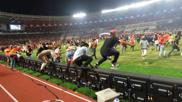 Suporter Persija Jakarta, The Jak Mania, memasuki lapangan SUGBK