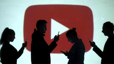 Siluet pengguna perangkat di antara logo YouTube.